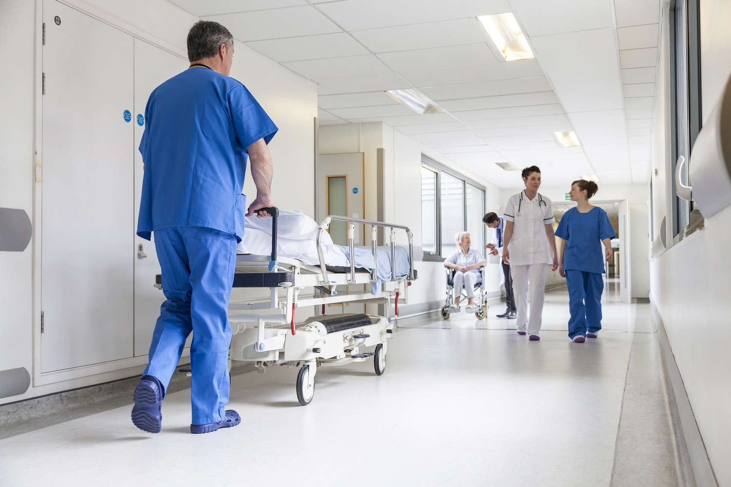 Logistica ospedaliera integrata — operatori con presidi in corridoio ospedaliero